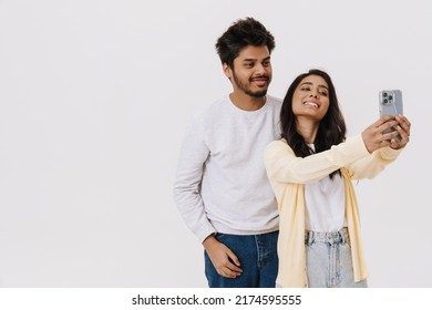 East Asian Young Man And Woman Smiling And Taking Selfie Photo With Cellphone Isolated Over White Background