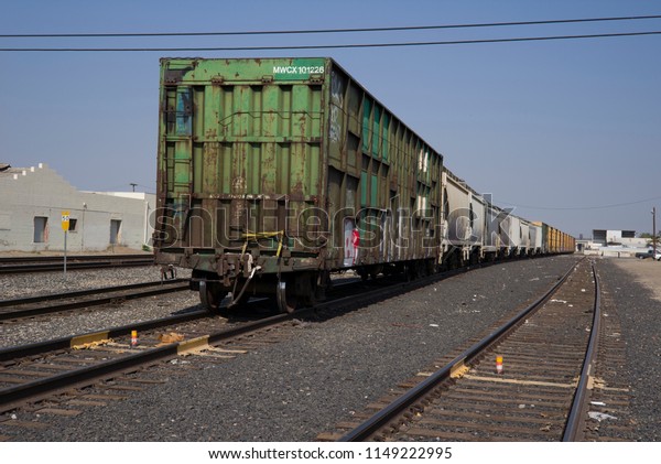 EAST BAKERSFIELD, CA - AUGUST 2, 2018: A\
string of box cars await a diesel electric locomotive to pull them\
to their destination.