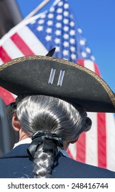 EAST BERLIN,PA-SEPTEMBER 14, 2013: Rear View Of Unidentified Man Dressed In Colonial Period Clothing Wearing Three Cornered Hat And Wig Looking Up At American Flag.