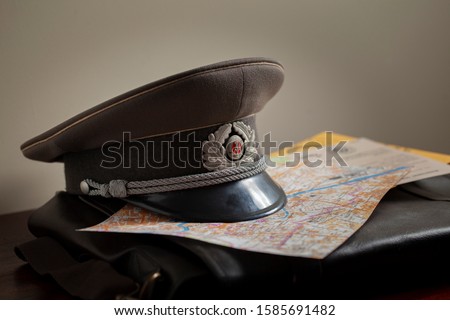 East German Stasi officer cap placed on a map of Berlin, a 1966 DDR document and briefcase.  Vladimir Putin 1980s, 1990s
