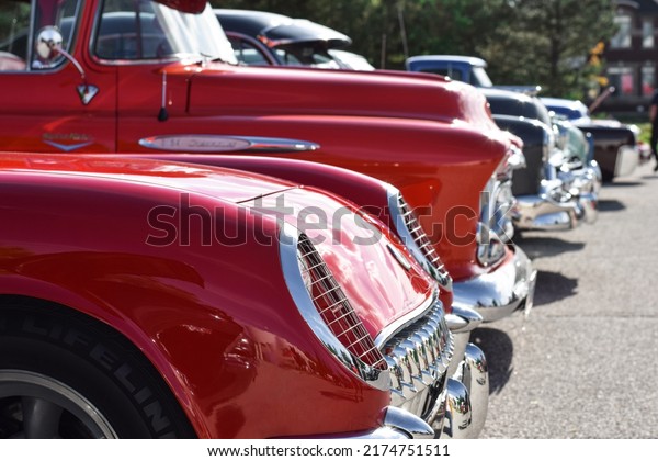 East Gwillimbury, Ontario, Canada - May 28,\
2022: Line up of parked vintage retro cars with closeup on red\
Chevrolet Corvette