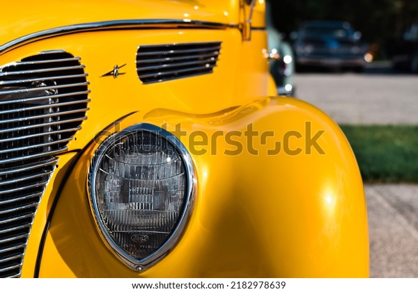 East\
Gwillimbury, Ontario, Canada - May 28, 2022: Closeup front\
headlight of the vintage retro yellow ford v8\
car
