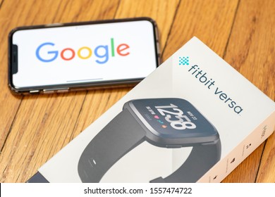East Hartford, Connecticut, USA – November 3, 2019: Fitbit Versa with google logo displayed on apple iPhone 11 Pro, Google’s parent company Alphabet acquired the Fitbit company.