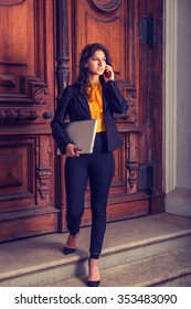 East Indian American Business Woman Working In New York, Wearing Black Blazer, Orange Shirt, Pants, Heels, Walking Down Office Doorway, Carrying Laptop Computer, Calling On Phone. Instagram Effect.