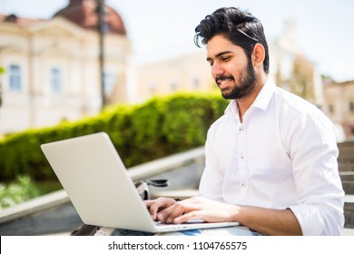 East Indian American College Student Sits On Stairs On Campus, Works On Laptop Computer.