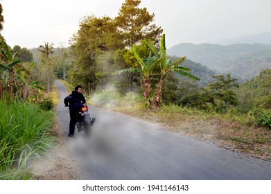 East Java Indonesia, March 23 2021 a man riding a motorcycle on the downhill road, performs a cool burnout attraction. in the afternoon