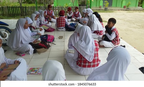 East Kalimantan, Indonesia (23/01/2020). Display of cute and happy elementary school children with lesson materials and notebooks sitting on the classroom terrace outdoors. Samarinda, Indonesia.