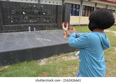 East Kalimantan, Indonesia (May 26, 2022) : A Little Girl Playing A Slingshoot Or Catapult. The Target Of The Shot Is The Mineral Water Bottles