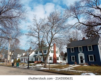 East Lansing, Michigan, USA - March, 1st, 2022: Butterfield Dr Street Off-campus. Residential Tree-lined Street With Houses Painted In Green And White. Last Snow On The Ground. No People. Blue Sky.