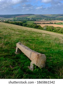 East Meon, UK - August 21, 2020:  A View Over The South Downs Village Of East Meon From Near Heyden Hill With A Stone Bench In The Foreground