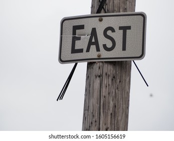 East Sign That Is Faded Posted On A Telephone Poll