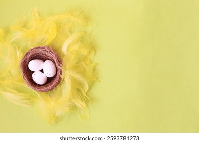 Easter background with Copy space for text. Flat lay.top view.decorative Bird's nest with three white eggs nestled among yellow fluffy feathers on a light greenish yellow background