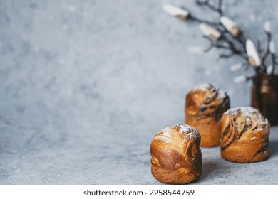 Easter background. Cruffin buns on sprinkled with powdered sugar with cherry blossoms on a gray background. Healthy holiday baking. High quality photo - Shutterstock ID 2258544759