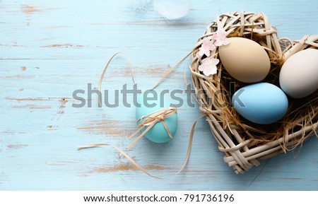 Easter background with Easter eggs in nest with shape of a heart on the blue wooden background . Top view with copy space.