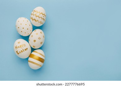 Easter background. Easter golden decorated eggs on blue background. Minimal easter concept. Flat Lay of Golden Easter Eggs