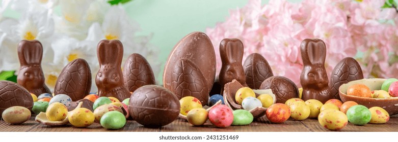 Easter background greeting card with holiday traditional confectionery, Easter egg hunt fun concept. Chocolate bunny, chocolate and candy Easter eggs on wooden background - Powered by Shutterstock