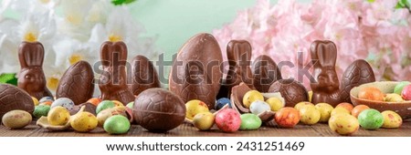 Easter background greeting card with holiday traditional confectionery, Easter egg hunt fun concept. Chocolate bunny, chocolate and candy Easter eggs on wooden background