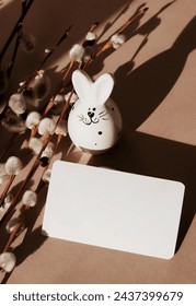 Easter background.Card mockup, empty blank paper,Easter funny bunny decor ,spring willow branches  in neutral brown color background top view flatlay. Copy space.sstkEaster