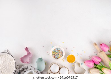 Easter baking background, ingredient for making Easter cookies, cakes, dessert with Easter chocolate eggs, sugar sprinkles, baking ingredients, flour, egg, milk, rolling pin, spring flowers top view