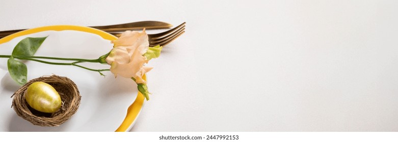 Easter banner. Golden egg in nest, delicate peach Eustoma flower on white and yellow plates, gold cutlery on white pink background. Copy space for text. Invitation template. - Powered by Shutterstock