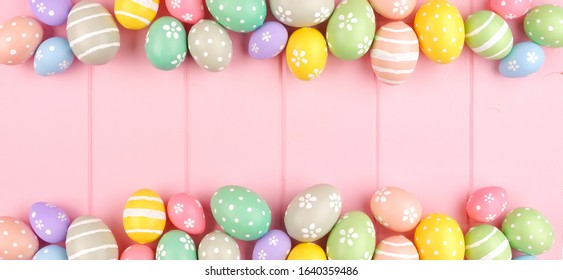 Easter banner with pastel colored egg double border over a pink wood background. Top view with copy space.