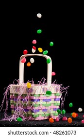 Easter Basket In Black Background With Candies Falling On It.