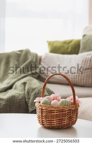 Easter Basket with Ester Eggs,  Plush Bunny and Spring Decor on White Table intoCozy Living Room