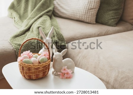 Easter Basket with Ester Eggs,  Plush Bunny and Spring Decor on White Table intoCozy Living Room