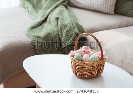 Easter Basket with Ester Eggs,  Plush Bunny and Spring Decor on White Table intoCozy Living Room