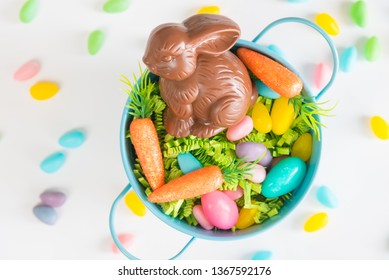 Easter Basket Filled With Easter Grass, Candy Eggs, Mini Carrots, And A Chocolate Rabbit