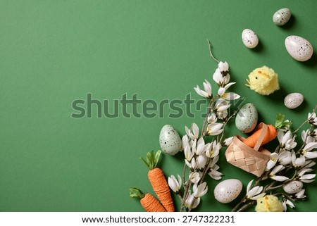 Easter border on green background with speckled eggs, spring blossoms, yellow chicks and wicker basket with left copy space