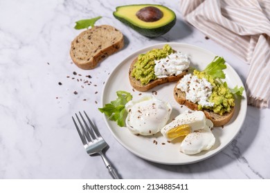 Easter breakfast or brunch. Delicious breakfast or snack - poached egg and cream cheese toast whole grain rye bread, avocado on a marble tabletop.