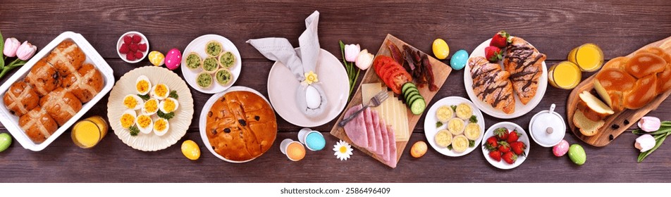 Easter breakfast or brunch table scene. Above view on a dark wood banner background. Breads, quiche and a variety of spring food items.