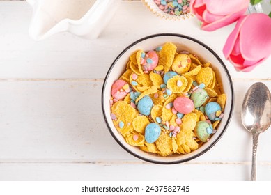 Easter breakfast cereals, corn flakes with Easter chocolate eggs and sugar sprinkles, pouring milk or yoghurt in corn golden breakfast cereals portion on Easter decorated table - Powered by Shutterstock