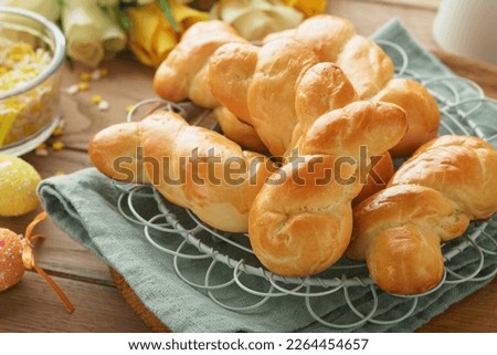 Easter breakfast Holliday concept. Easter bunny buns rolls with cinnamon made from yeast dough with orange glaze, easter decorations, colored eggs on old wooden background. Easter Holliday card.