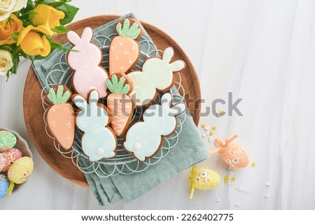 Easter breakfast Holliday concept. Easter gingerbread shape of bunny and carrot with cinnamon with colored glaze, easter decorations, colored eggs on white spring background. Easter Holliday card. 