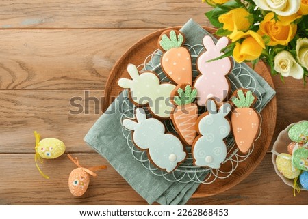 Easter breakfast Holliday concept. Easter gingerbread shape of bunny and carrot with cinnamon with colored glaze, easter decorations, colored eggs on old wooden background. Easter Holliday card. 