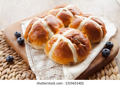 Easter breakfast with traditional hot cross bun and coated small chocolate eggs.