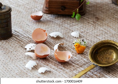 Easter, broken eggshells on burlap, standing small yellow chicken, left copper strainer, coffee grinder in background.
