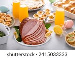 Easter brunch on large table with spiral sliced ham, quiche, deviled eggs and hot cross buns with Easter decor