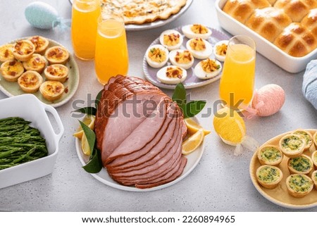 Easter brunch table with ham, quiche, hot cross buns and deviled eggs and mimosas