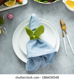 Easter Brunch Table Setting With A Napkin On A Plate, Colorful Eggs And Bunny Ears Decoration