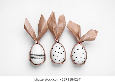 Easter bunnies made of craft paper and eggs on white background, flat lay