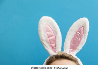 Easter Bunny Ears. Female Wearing White Bunny Ears Costume Against A Bright Blue Background