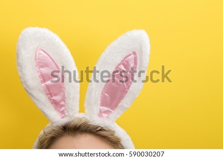Easter bunny ears. Female wearing white bunny ears costume against a bright yellow background