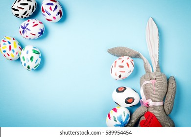 Easter bunny on a blue background with Easter eggs. Rabbit. Space for text. Black lettering on a heart.
