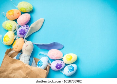 Easter bunny in a paper bag with Easter eggs. Blue background. Space for text. The inscription on the package. 