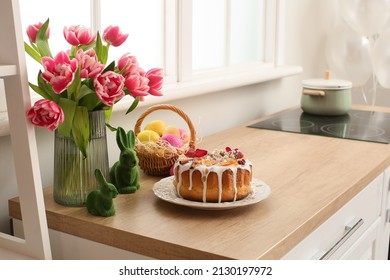 Easter cake, basket of eggs and tulips on kitchen counter near white wall