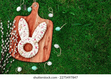 easter cake. easter bunny with easter eggs and willow on green grass with copy space for your text