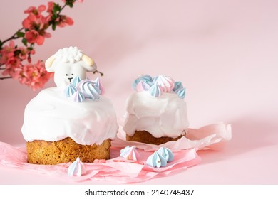Easter cake with white icing and blue meringues Easter decorative lamb on a pink background with spring cherry blossoms and copy space. Easter Ukraine orthodox sweet bread. Easter card concept.
